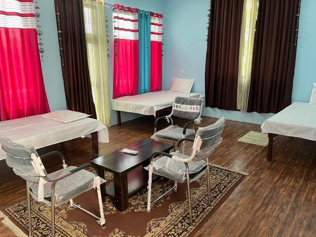 Habitación con 2 camas, sillas y mesa. en Shri SeetaRam Home Stay Near Shri Ram Janmabhoomi Mandir Ayodhya, en Ayodhya