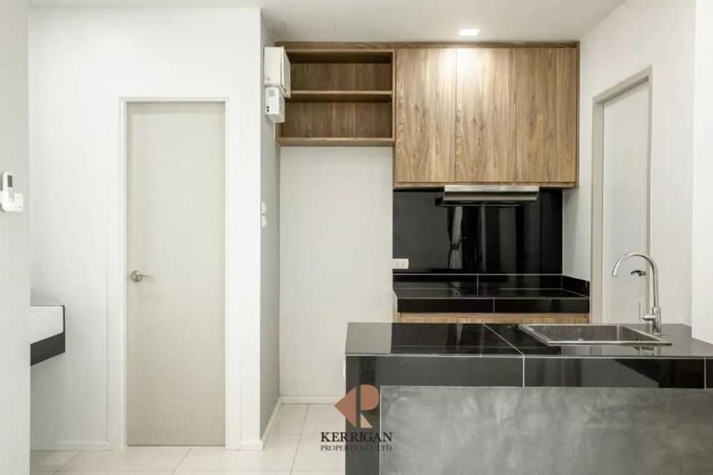 a kitchen with a black counter top and wooden cabinets at Malada in Chiang Mai