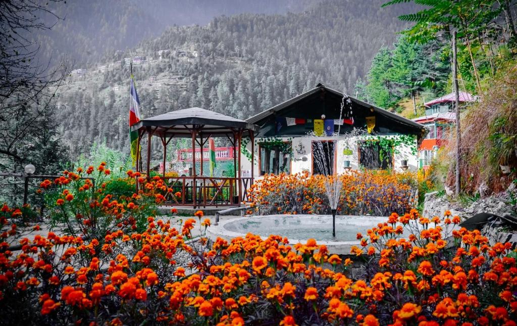 un giardino con fiori d'arancio e un gazebo di Himtrek Camps Jibhi a Jibhi