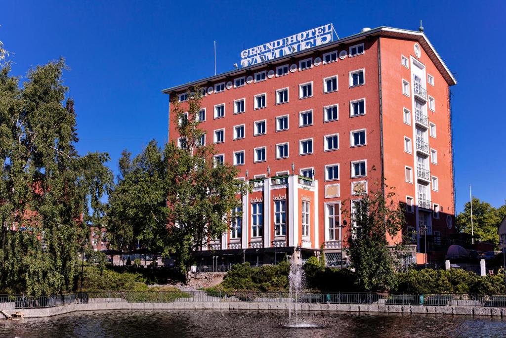 a large red building with a water fountain in front of it at Radisson Blu Grand Hotel Tammer in Tampere