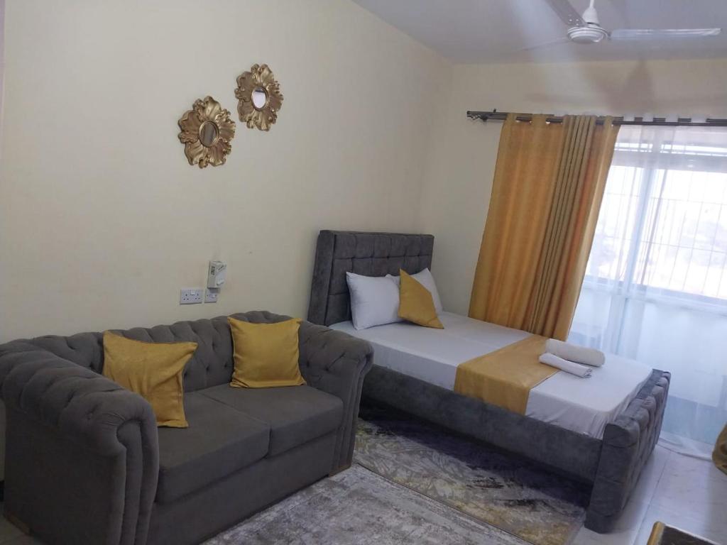 a bed and a couch in a living room at Lux Suites Cinemax Studio Apartments in Kisauni