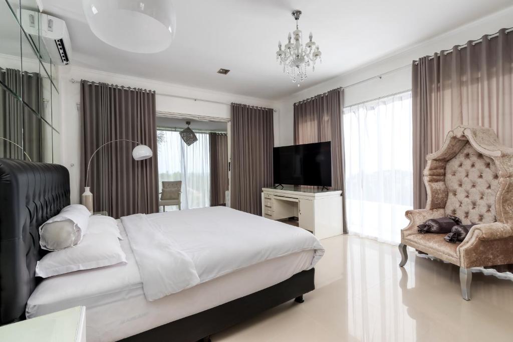 a bedroom with a bed and a tv and a chair at SunnyRent. Luxury TJ White Villa & Room in Ungasan