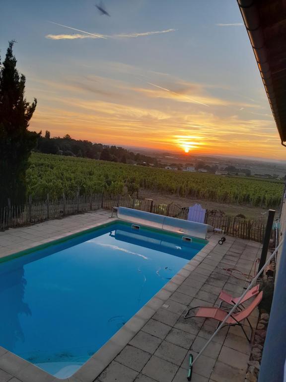 une piscine avec vue sur le coucher du soleil en arrière-plan dans l'établissement La côte des Blancs - Domaine viticole & maison d'hôtes, à Vinzelles