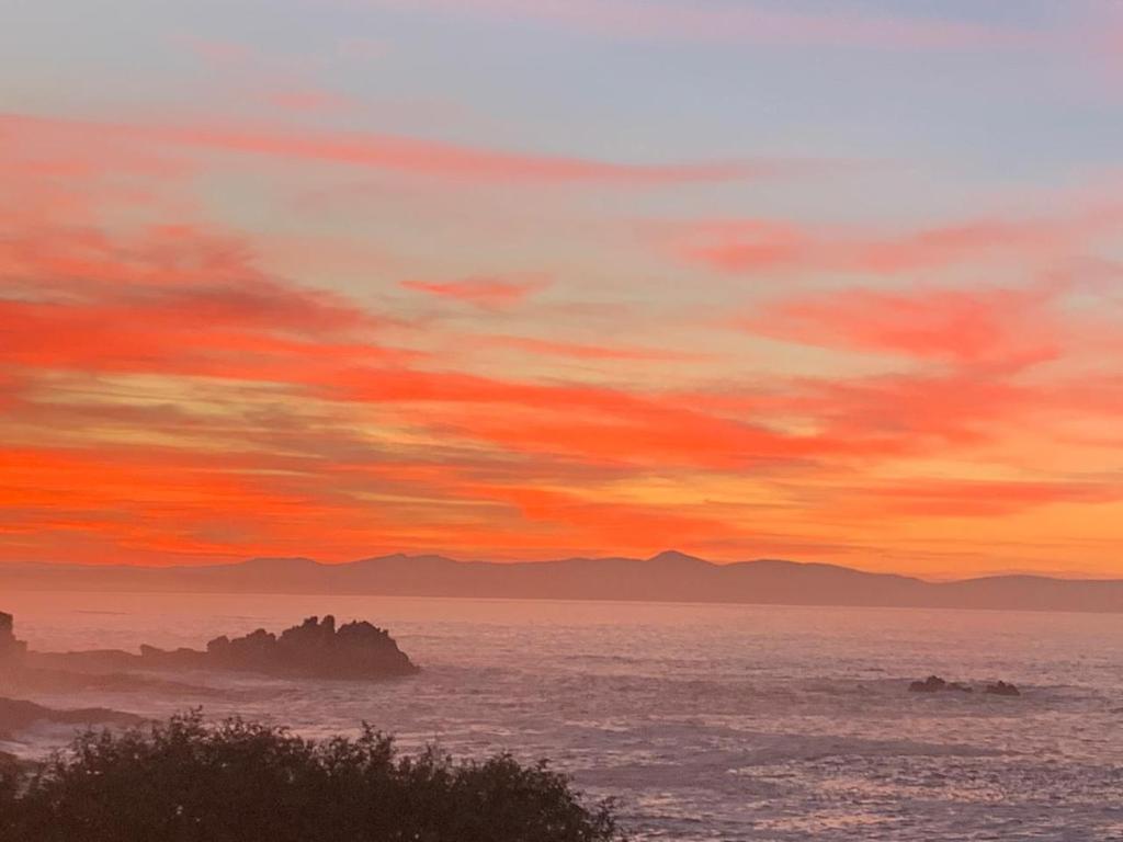 um pôr-do-sol sobre o oceano com montanhas ao fundo em Boutique Ocean Views - incorporating Wendy's em Hermanus