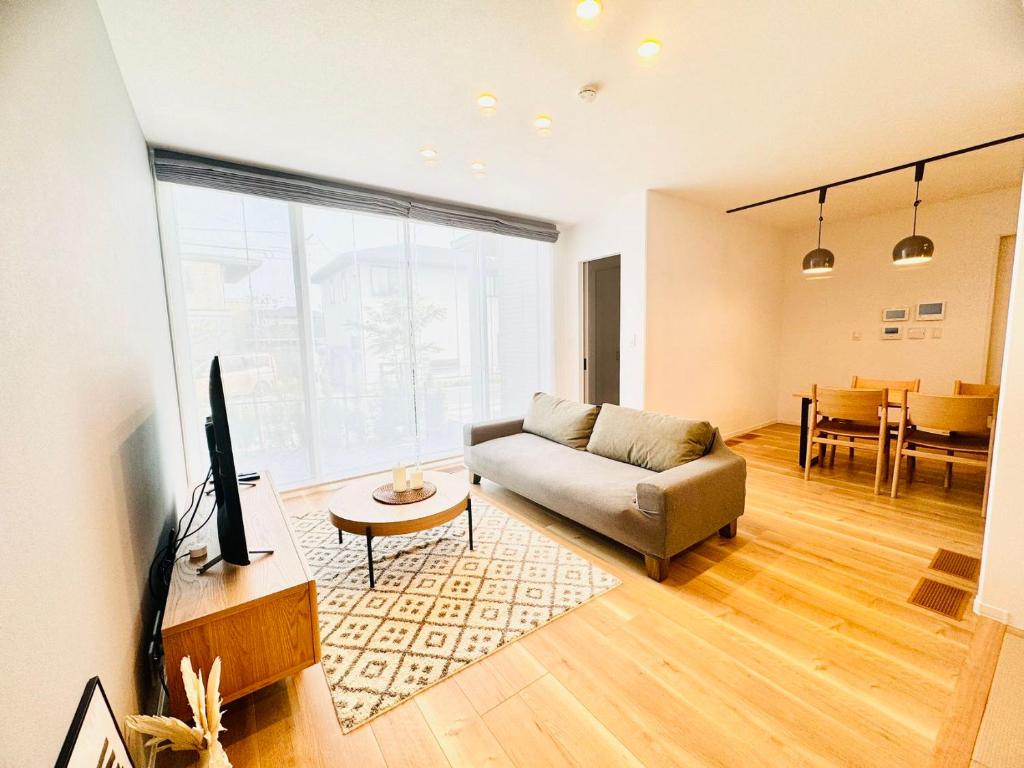 a living room with a couch and a tv in it at Akikawa Koshi 2 プレミアム鉄骨 一棟貸切ヴィラ in Yuge