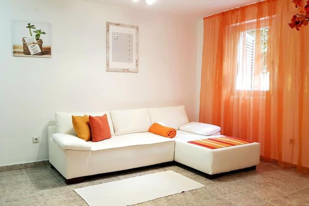 een woonkamer met een witte bank en een raam bij Apartment with a garden Petrovac in Petrovac na Moru