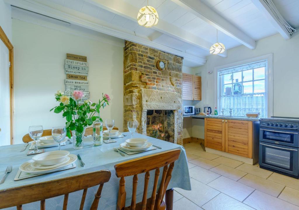 cocina con mesa con sillas y chimenea en Alice Cottage, en Robin Hood's Bay