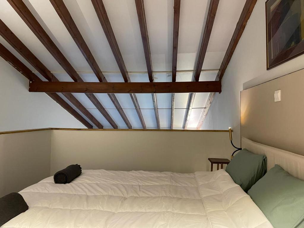 sypialnia z białym łóżkiem i drewnianym sufitem w obiekcie Calming mountain view apartment w Nikozji