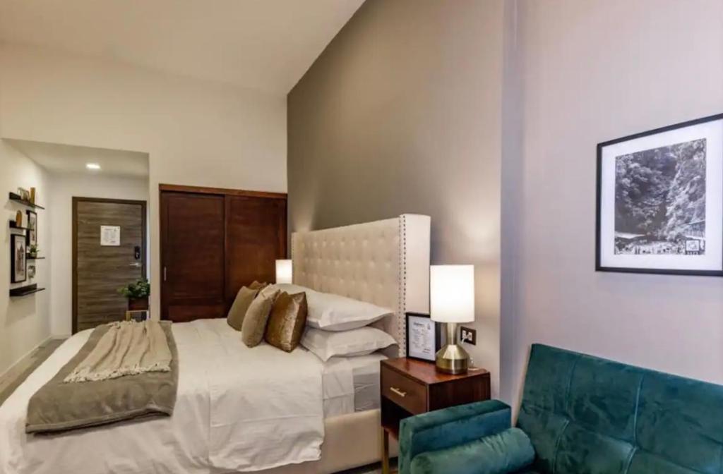 1 dormitorio con 1 cama grande y 1 silla azul en Central Park Jr. Suites en Quetzaltenango