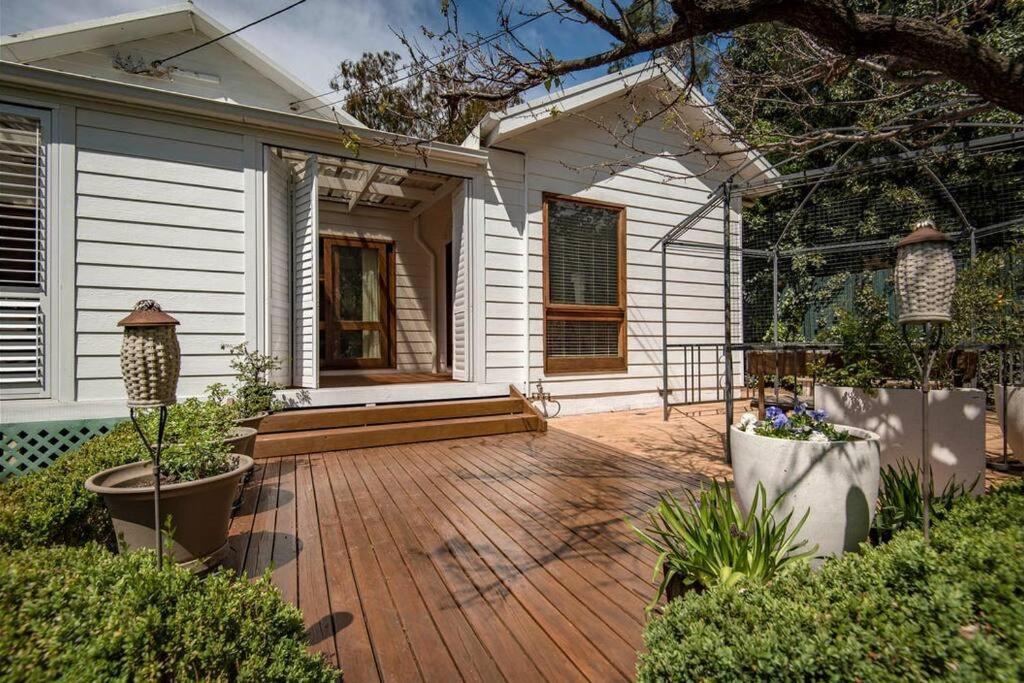 un porche de una casa con terraza de madera en Capital Cottage, en Narrabundah