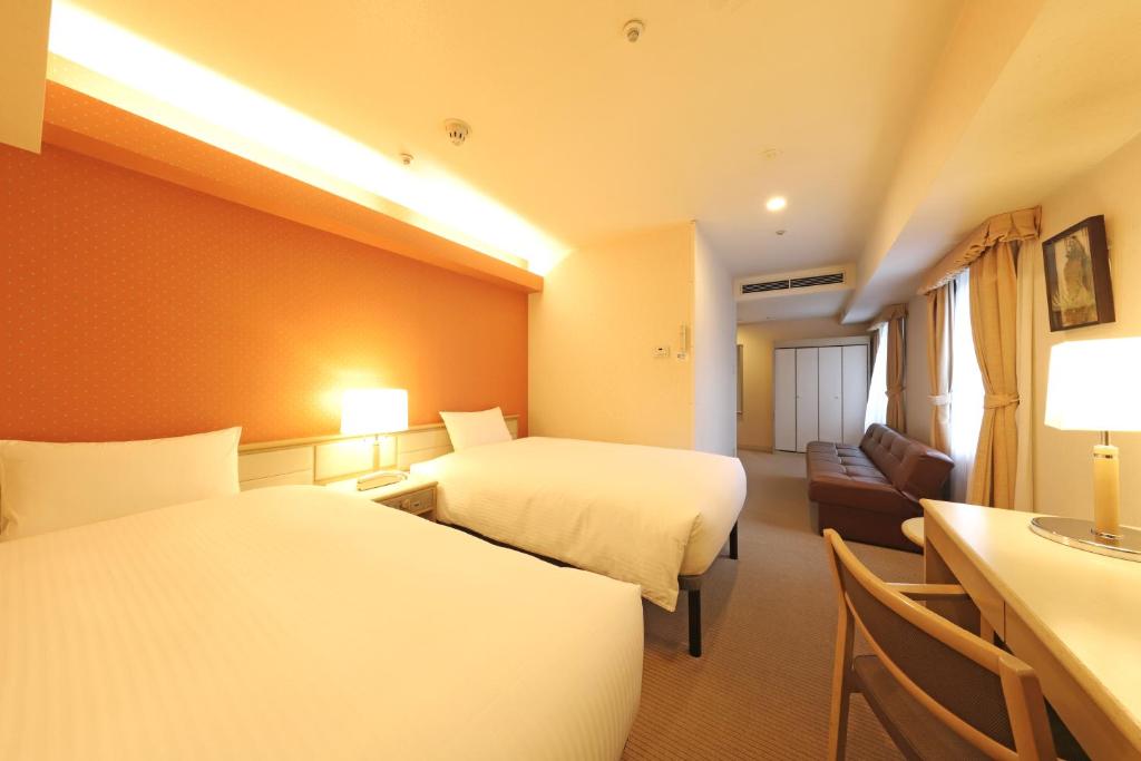 a hotel room with two beds and a couch at Shin-Yokohama Kokusai Hotel in Yokohama