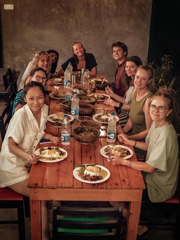 een groep mensen die rond een houten tafel zitten bij Hive Ella - Hostel in Ella