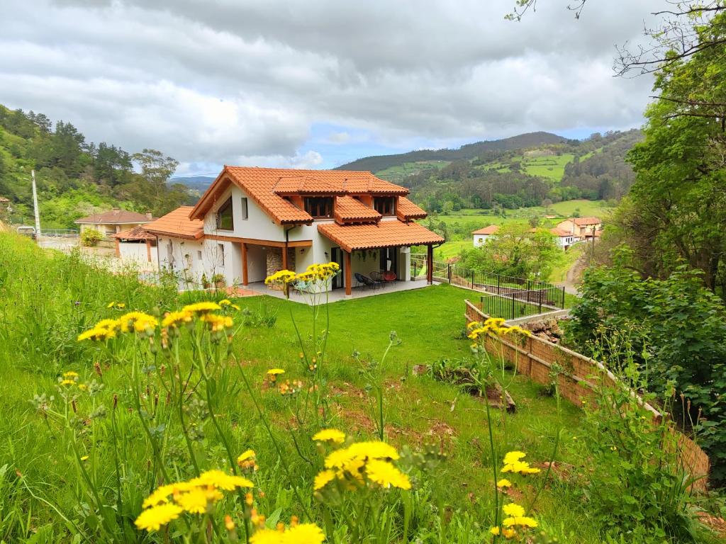 una casa en una colina con un campo de flores amarillas en Reguero Gato, Apartamentos Rurales 3 llaves en Candamo