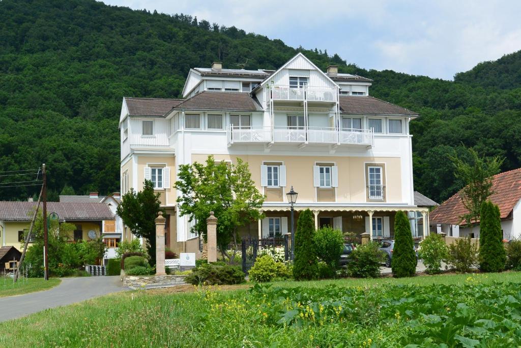 a large white house with a mountain in the background at Villa Thalhof in Bad Gleichenberg