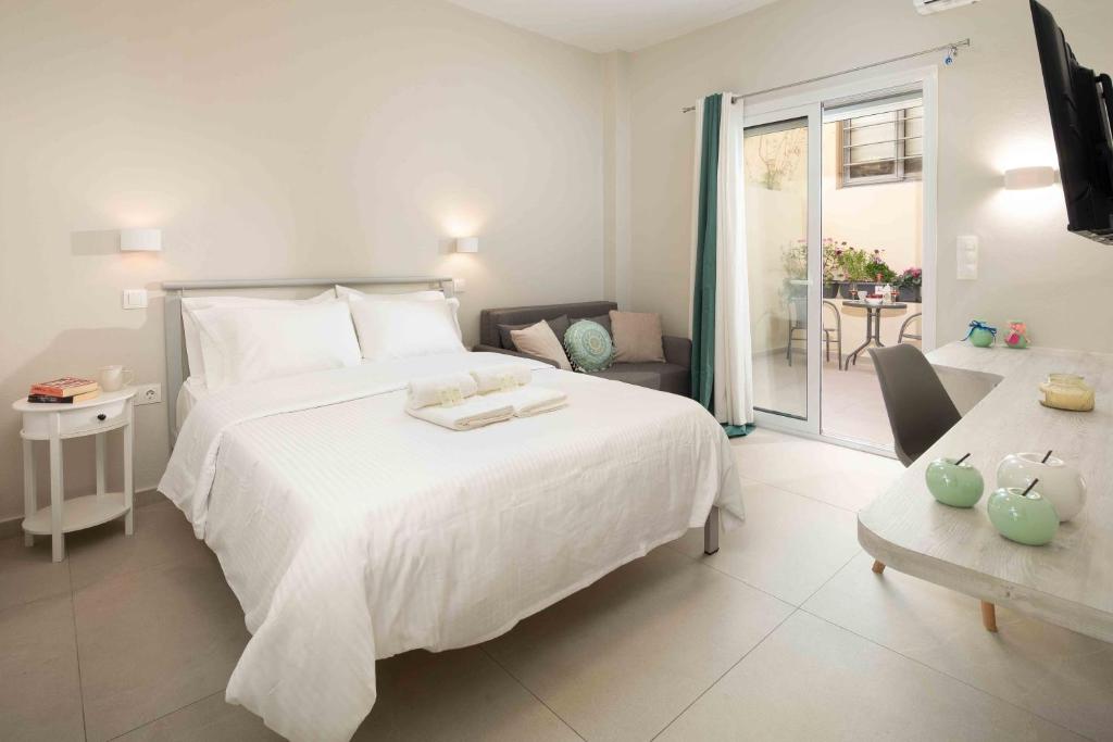 Un dormitorio con una gran cama blanca y un balcón. en Yard Studio by CorfuEscapes, en Corfú