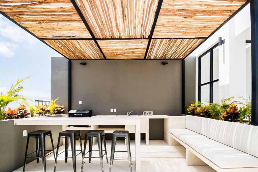 an outdoor kitchen with a white table and stools at Joya de la Zazil 20 Av ROOFTOP POOL Walk to Playa Mamitas Coco Beach & 5 in Playa del Carmen