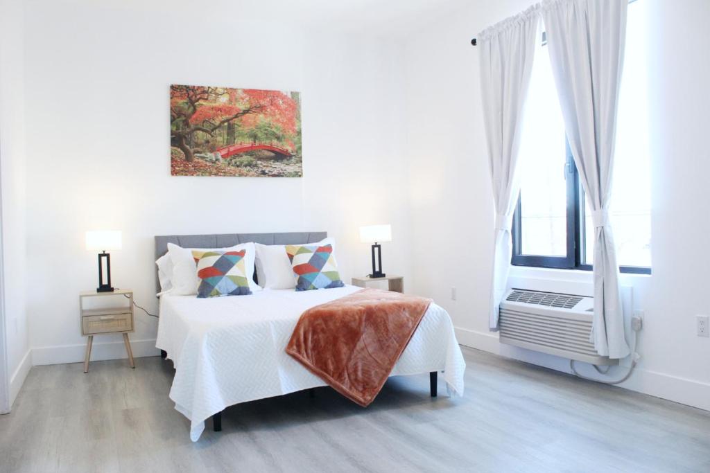une chambre blanche avec un lit et un tableau au mur dans l'établissement Cozy Stylish Apartment near Newark, NJ Airport, à Elizabeth