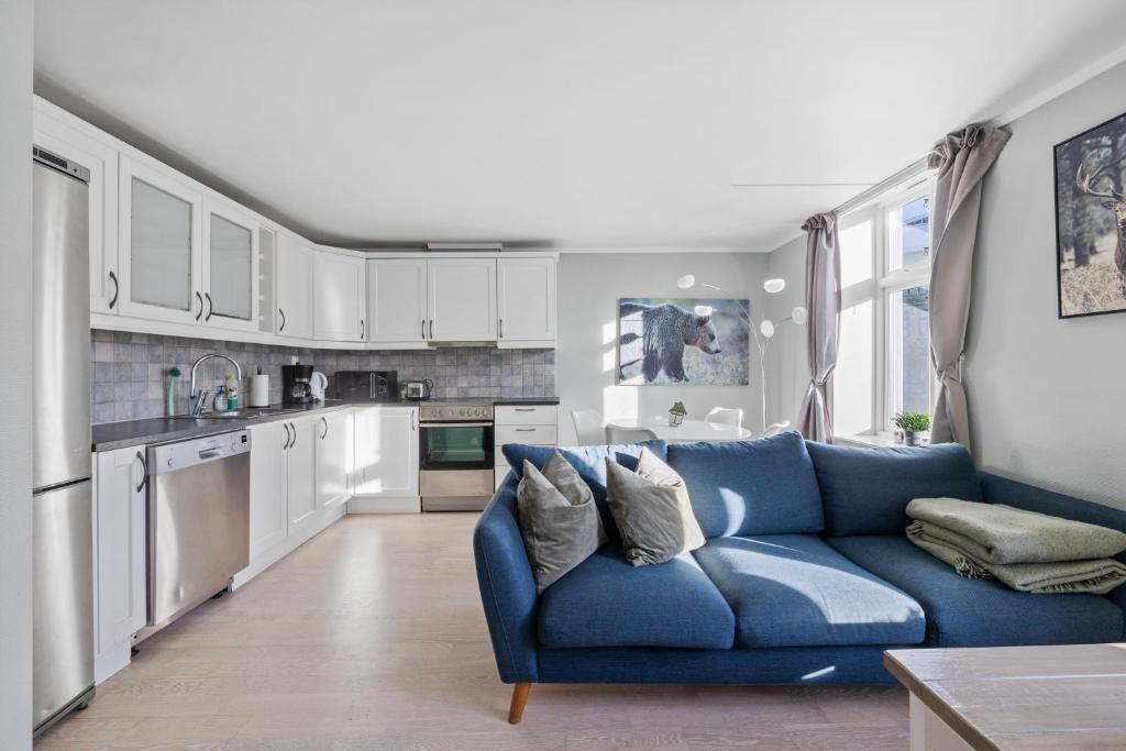 a living room with a blue couch in a kitchen at Beautiful space with balcony in Oslo