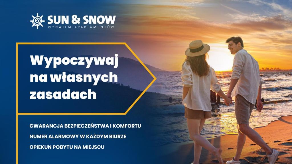 隱海市的住宿－Apartamenty Sun & Snow Słoneczne，日落时分在海滩上散步的夫妇