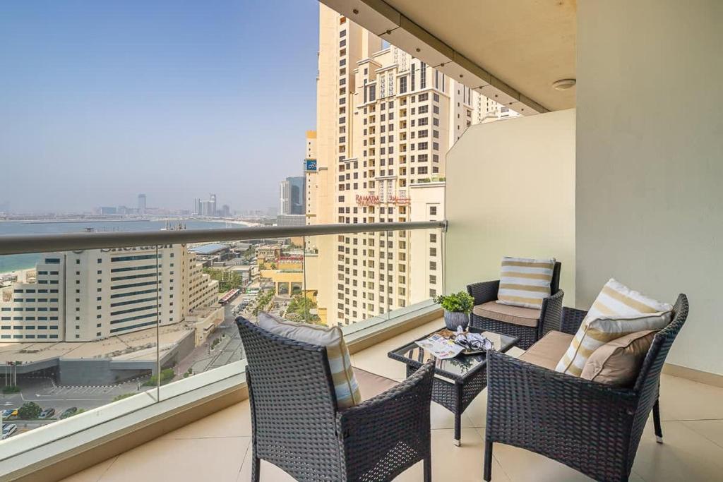 a balcony with chairs and a table and a large window at Frank Porter - Dorra Bay in Dubai