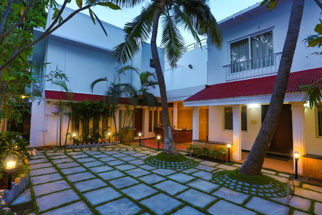 a house with two palm trees in front of it at Avenue 11 Boutique Residences, Poes Garden Chennai in Chennai