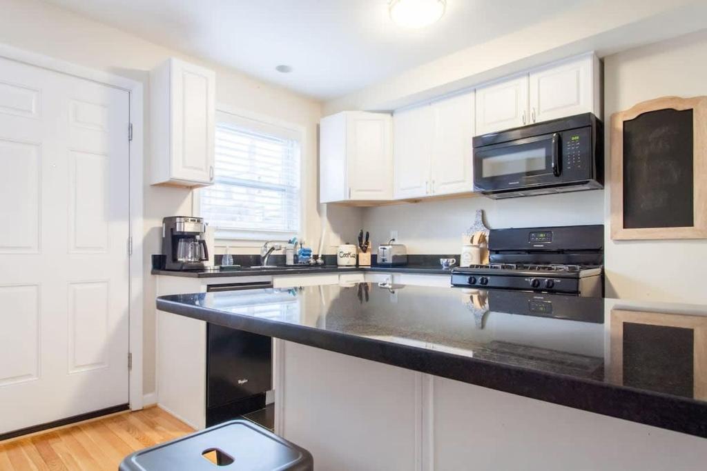 a kitchen with white cabinets and a black counter top at Transit-Friendly Home Old Town Parking in Alexandria