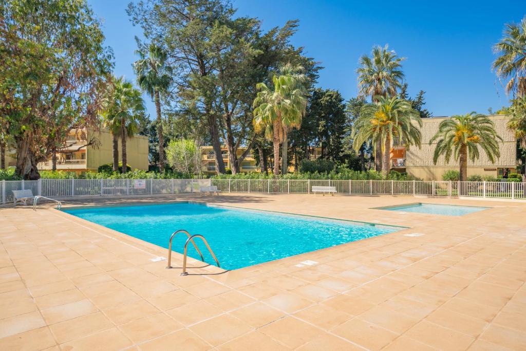 ein Pool mit Palmen im Hintergrund in der Unterkunft Spacieux 2pièces à5min de plages in Antibes