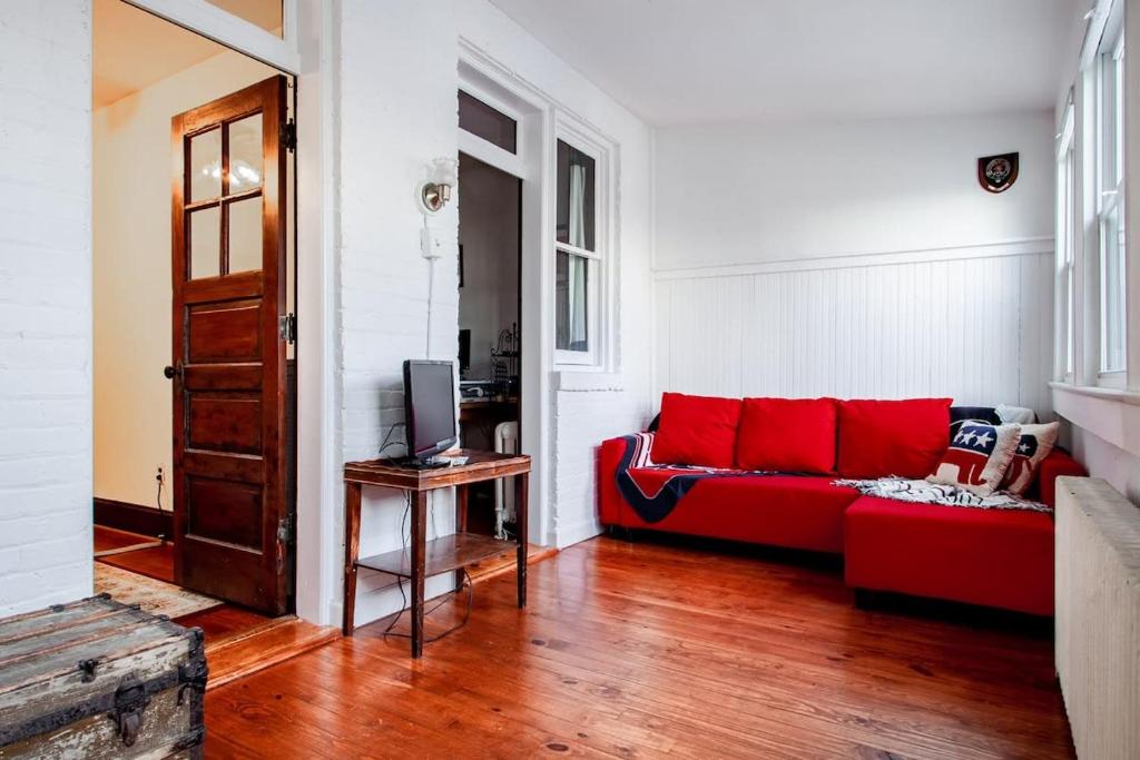 a living room with a red couch and a television at The E St Retreat Lovely 3-BR Nestled between H St & Eastern Market in Washington, D.C.