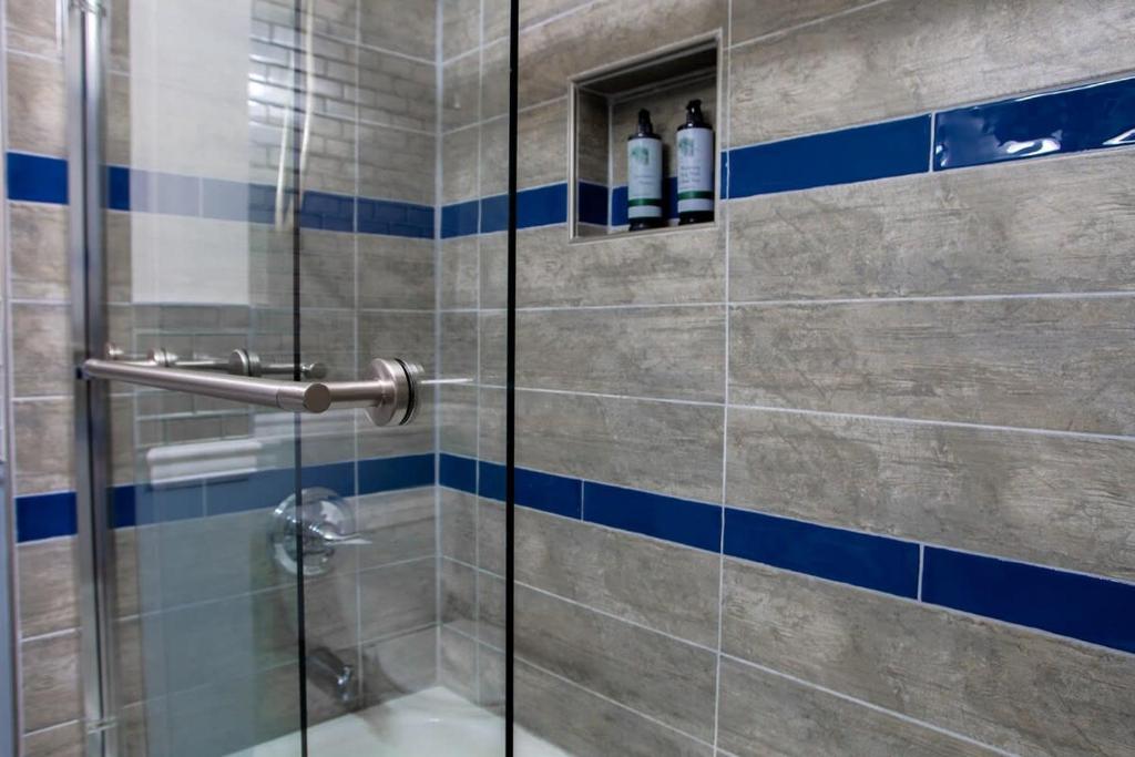 a bathroom with a shower with blue and white tiles at NoMA 3BR Townhome - UnionMarket H St Streetcar in Washington, D.C.