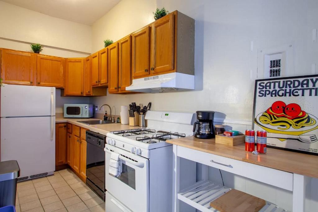 a kitchen with white appliances and wooden cabinets at Classy 1-BR Flat Nestled Between Dupont & Logan in Washington, D.C.