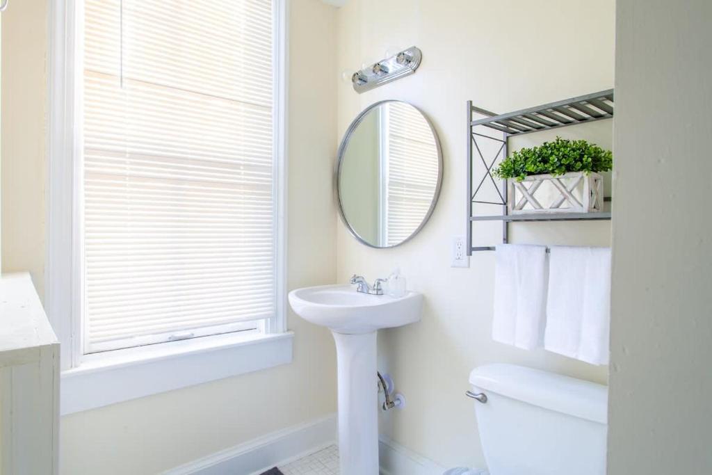 a white bathroom with a sink and a mirror at Classy 1-BR Flat Nestled Between Dupont & Logan in Washington, D.C.