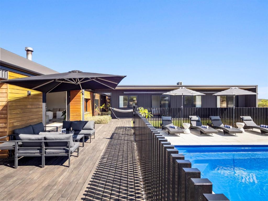 a pool with chairs and umbrellas next to a house at Casa Burnside in Margaret River Town