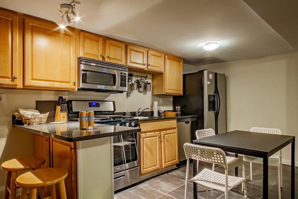 a kitchen with wooden cabinets and a table with chairs at Rest Easy in this Bloomingdale English Basement in Washington, D.C.