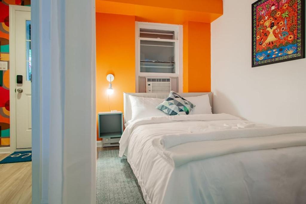 a bedroom with two beds and an orange wall at Over the Moon About C Adams Morgan METRO subway Rock Creek Park in Washington, D.C.