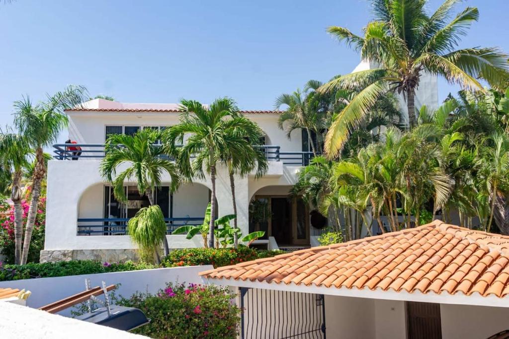 a white house with palm trees in front of it at Villa Calafia Spacious Home w Private Tennis in Cabo San Lucas