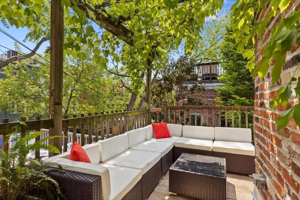 a white couch on a patio with red pillows at Historic Capital Hill Home and Carriage House in Washington, D.C.