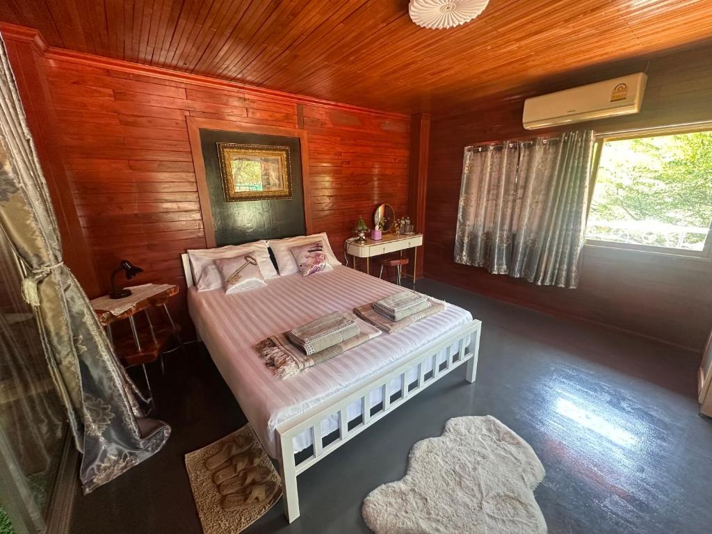 um quarto com uma cama num quarto de madeira em ไททำดี โฮมสเตย์ Taitam-D Homestay em Ta Phraya