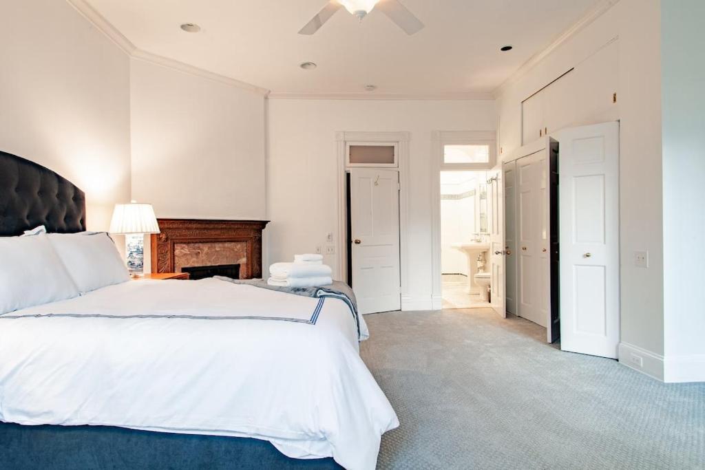 a white bedroom with a large bed and a hallway at LUXE Kalorama 5-BR Townhome Close to Dupont Circle in Washington, D.C.