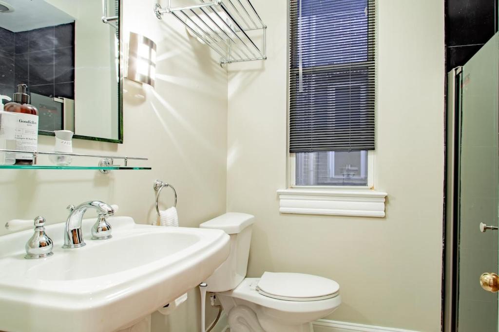 a white bathroom with a sink and a toilet at LUXE Kalorama 5-BR Townhome Close to Dupont Circle in Washington, D.C.