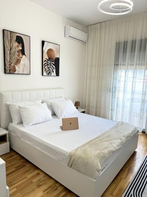 a white bedroom with a bed with a laptop on it at Sol Apartment - 2 Bedrooms in Shkodër