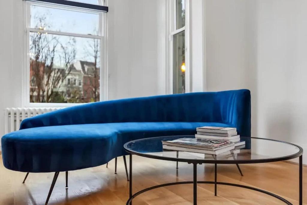 a blue couch in a living room with a glass table at H St DC Haven 4-BR Homestay in Washington, D.C.