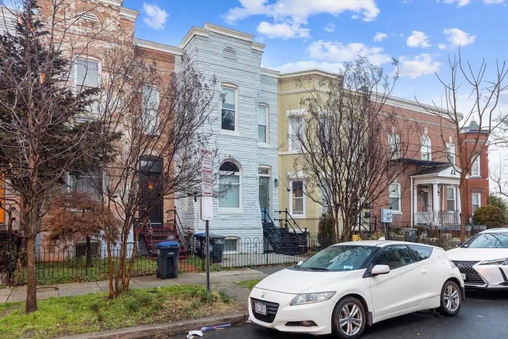 a white car parked in front of houses at H St DC Haven 4-BR Homestay in Washington, D.C.