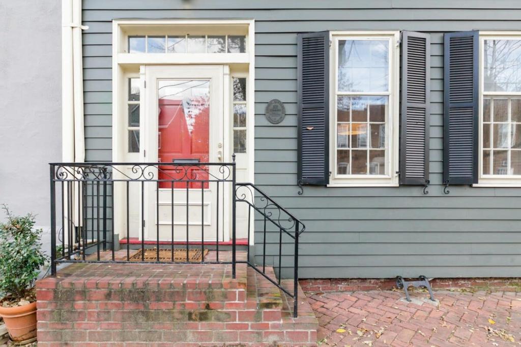 a blue house with a red door and a cat on the stairs at Historic Charming Home in Old Town in Alexandria
