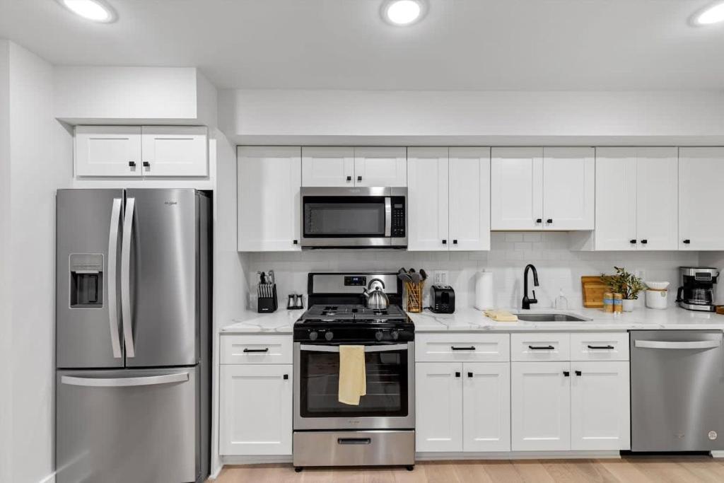 a kitchen with stainless steel appliances and white cabinets at Excellent 2-BR Condo in Hip Area of DC in Washington, D.C.