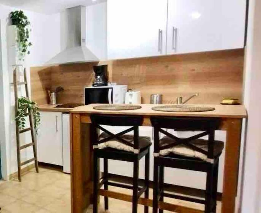 une cuisine avec deux tabourets de bar à un comptoir dans l'établissement Studio Centre historique Carpentras : Mya lee, à Carpentras