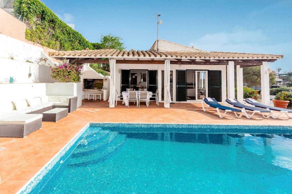 a villa with a swimming pool and a house at Villa Kingfisher in Cala Llonga