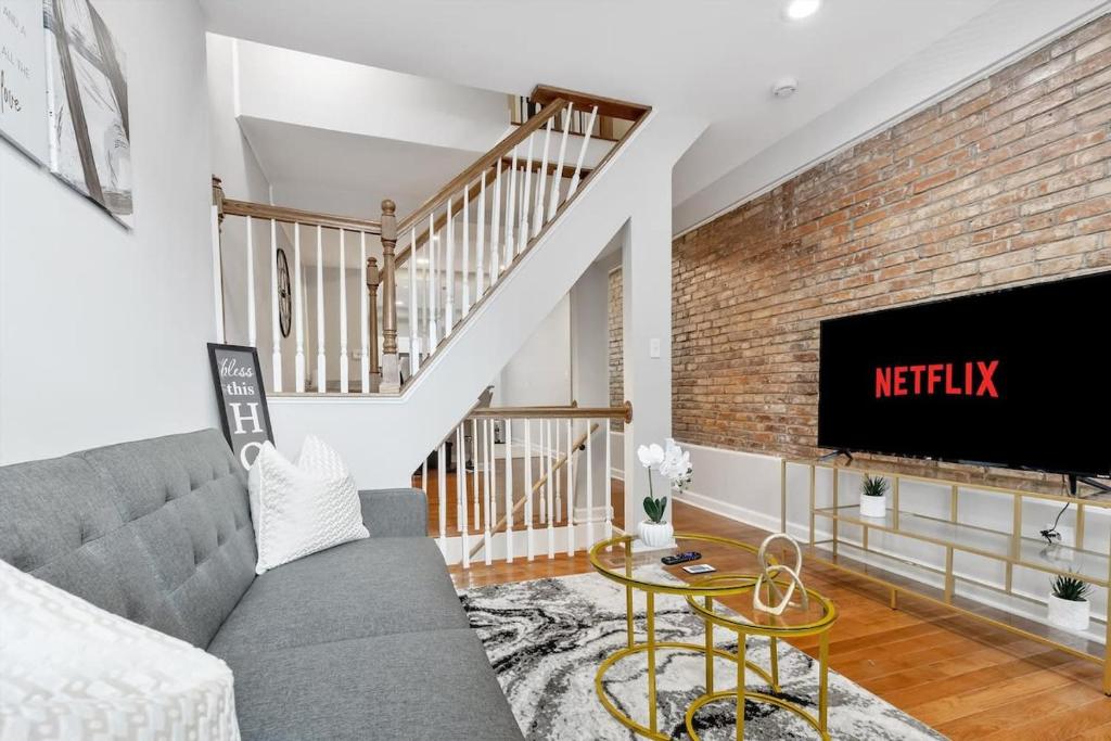 a living room with a gray couch and a brick wall at Charm City Homestay in Washington Village in Baltimore