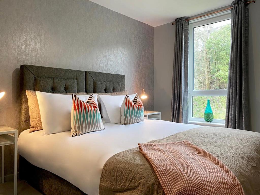 ein Schlafzimmer mit einem großen Bett mit Kissen und einem Fenster in der Unterkunft Beautiful West End Flat with Private Parking in Glasgow
