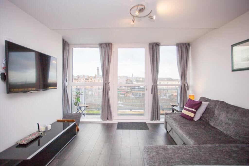 a living room with a couch and a large window at Beautiful Flat with Panoramic Views over the City in Glasgow