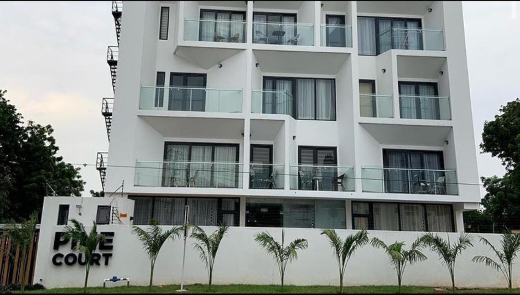 un bâtiment blanc avec des palmiers devant lui dans l'établissement The Pine Court, à Accra